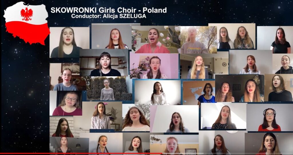 Zdjęcie stanowi zrzut ekranu komputera, na którym widzimy kilkadziesiąt okienek ze śpiewającymi dziewczętami. W lewym górnym rogu znajduje się wizerunek mapy Polski na biało-czerwonym tle, z czerwonym orłem w górnej, białej części. Obok, nad okienkami widnieje napis: SKOWRONKI Girls Choir. Conductor: Alicja Szeluga.