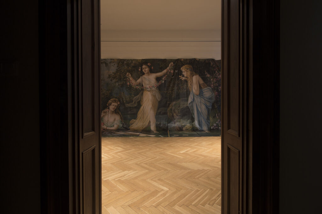 W otwartych drzwiach w oświetlonym pomieszczeniu fragment prezentowanego wydruku wielkoformatowego